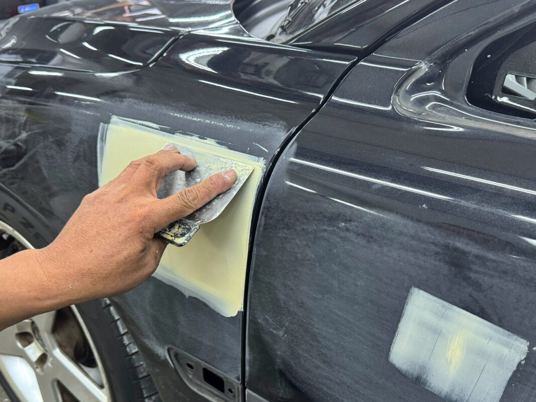 A technician patching an imperfection on the Volvo S60R's bodywork before painting.