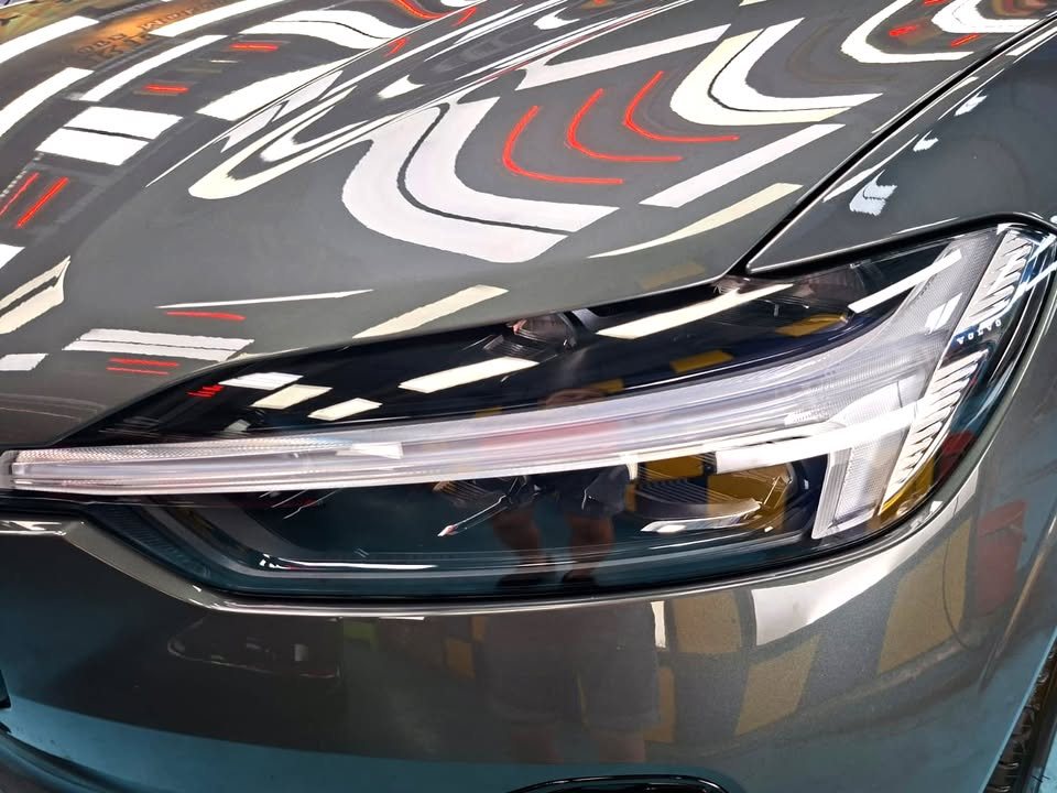 Close-up of the headlight below a glossy grey bonnet edge.