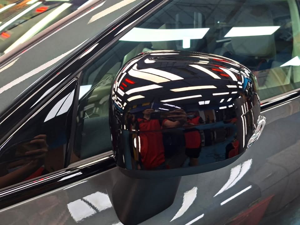 Gloss black side mirror cap reflecting the workshop.