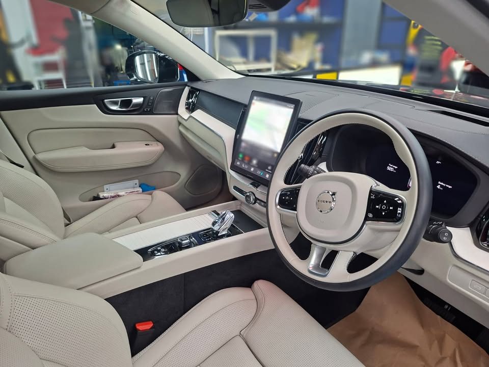 Cabin with cream leather seats, steering wheel and portrait touchscreen.