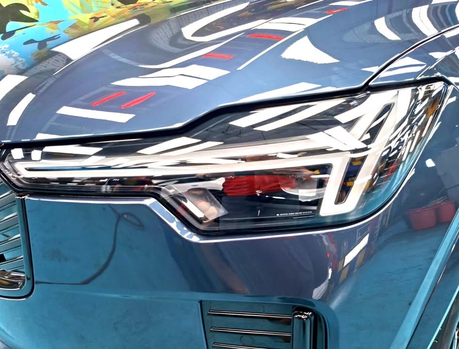 Close-up of the XC90 headlight against blue paint.