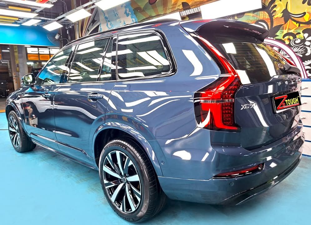 Rear three-quarter view of the blue Volvo XC90 showing the tail lights.