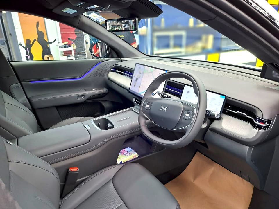 Xpeng G6 cabin with grey seats, steering wheel and wide dashboard screen.