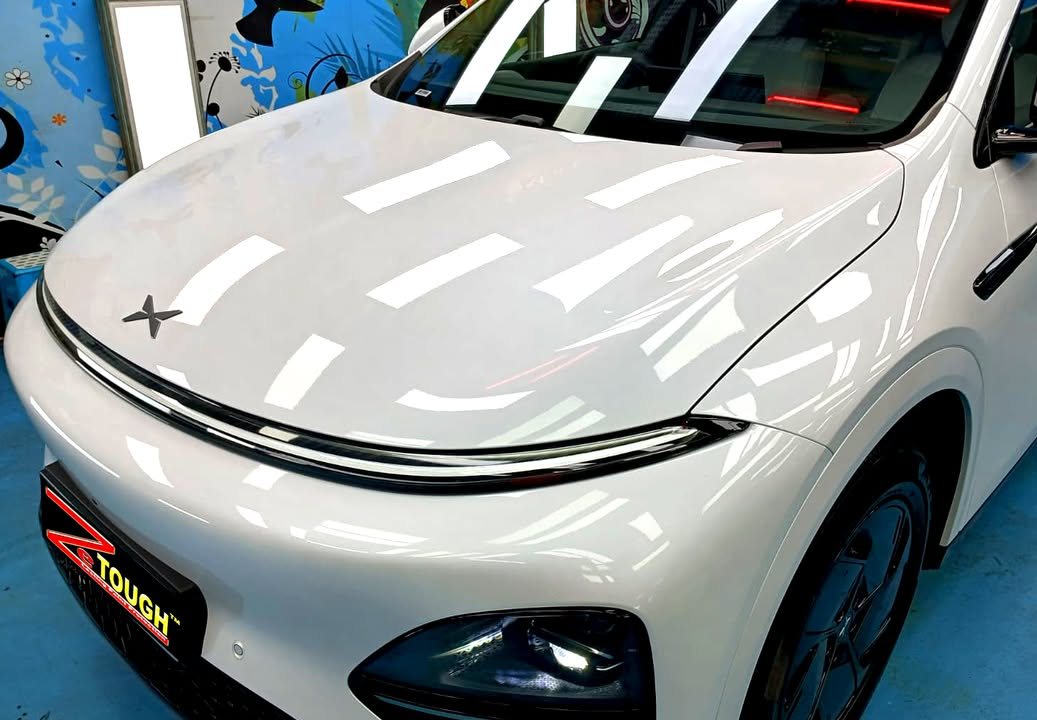 Close-up of the white bonnet and front light bar with workshop lights reflected.