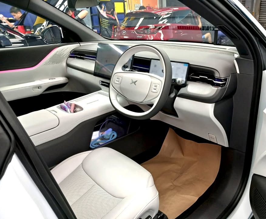 Interior with light grey seats, steering wheel and dashboard screens.