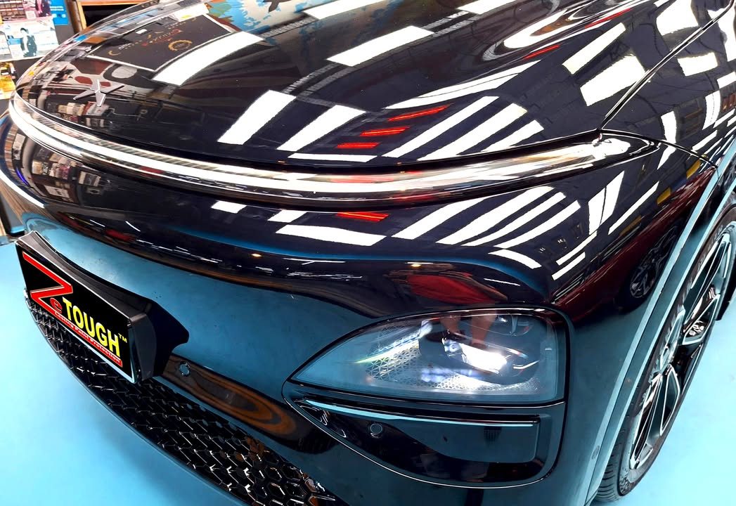 Front of the black G6 showing the light bar and headlight, with sharp reflections in the bonnet.