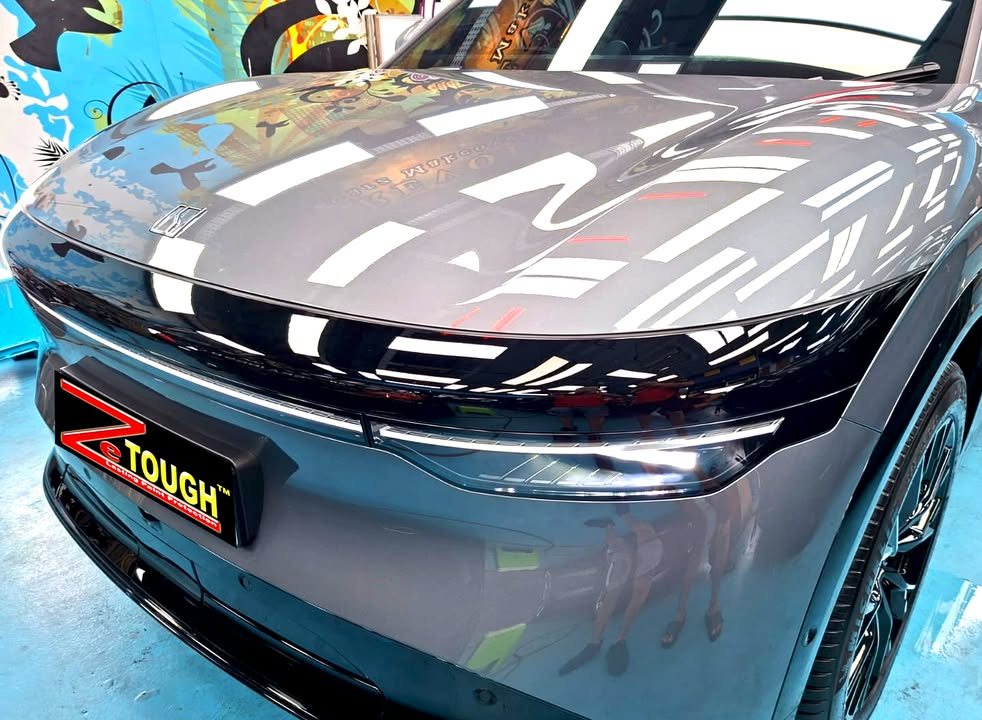 Close-up of the Zeekr 7X front end with workshop lights reflected in the grey bonnet.