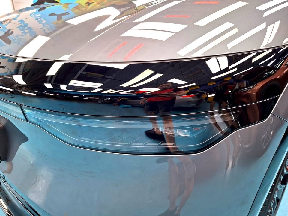 Close-up of the 7X headlight with ceiling lights reflected in the grey paint.