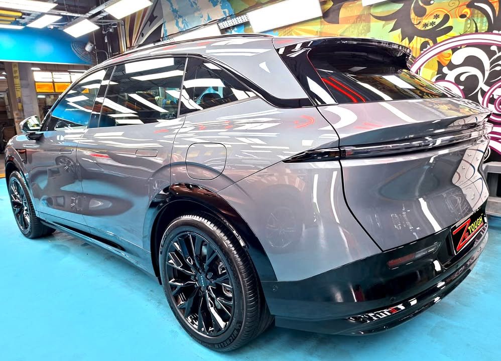Rear three-quarter view of the grey Zeekr 7X showing the full-width tail light.
