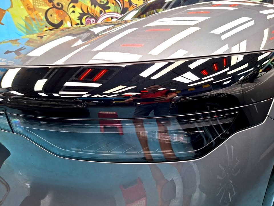 Close-up of the Zeekr 7X front light strip with workshop lights reflected in the grey paint.